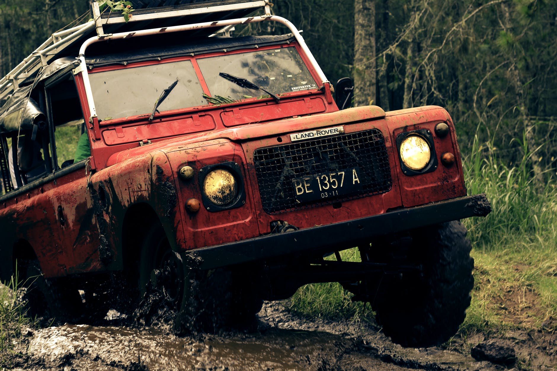 red car on muddy road near trees